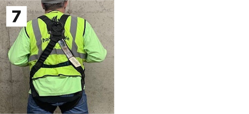 construction worker demonstrating step 7 of wearing a safety harness