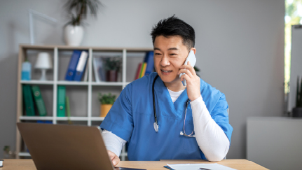 nurse talking on phone while looking at laptop