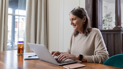 man sitting on a couch with a laptop and woman sitting on the floor with a tablet