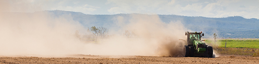 tractor in field with cloud of dust