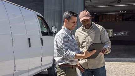 A small business owner smiles while holding a tablet