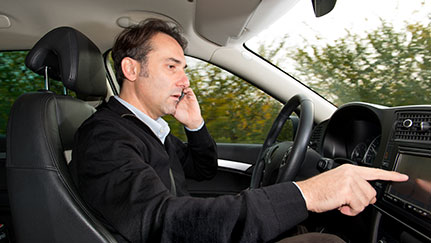 driver talking on the phone and tapping dashboard screen while driving