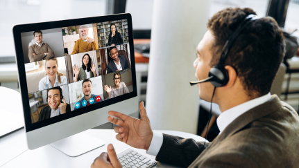 A person participating in a virtual meeting with multiple attendees on a computer screen.