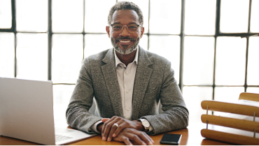 A smiling financial professional looks confident because of his growing book of business.