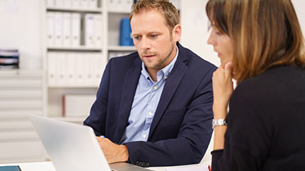 coworkers reading business continuity strategies on laptop screen