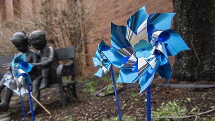 blue and silver pinwheels in front of a sculpture of children
