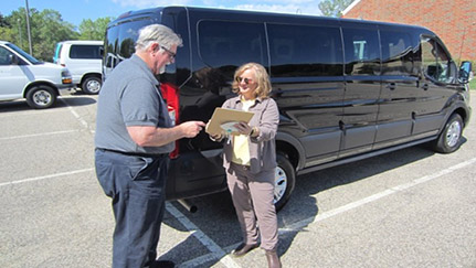 driver and trainer standing near fleet vehicle