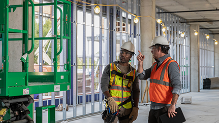 Construction workers inspecting elevated lift equipment.